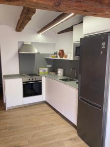 a kitchen with white cabinets and a black refrigerator at Casa Román in Albarracín