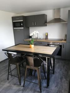 eine Küche mit einem Tisch und Stühlen mit einer Vase aus Blumen in der Unterkunft La Maison Bleue in Saint-Étienne-lès-Remiremont