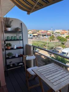 einen Balkon mit einem Tisch und einer Bank auf einem Balkon in der Unterkunft Chez Armelle in Port-la-Nouvelle