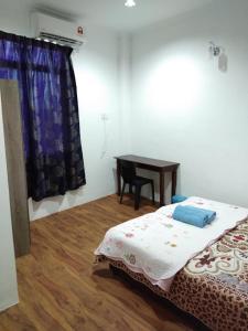 龍運的住宿－Alin Roomstay Dungun，一间卧室配有一张床、一张桌子和一张桌子
