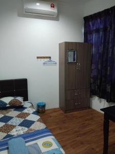 a bedroom with a bed and a wooden cabinet at Alin Roomstay Dungun in Dungun