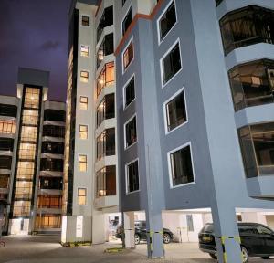 een hoog gebouw met auto's geparkeerd voor het bij Bee Furnished apartments 3 in Nakuru