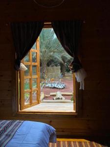 a window in a bedroom with a view of a yard at كوخ آفيري Aviary Hut in AlUla