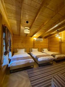 a bedroom with three beds in a wooden room at كوخ آفيري Aviary Hut in AlUla