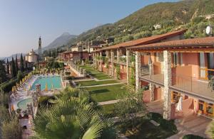 a resort with a swimming pool and mountains in the background at Residence Borgo Dei Limoni - Appartamenti con Garage in Gargnano