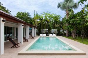 a swimming pool with chairs and a house at Houses of Sunny in Bang Sare
