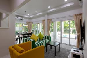 a living room with yellow and green chairs and a table at Houses of Sunny in Bang Sare