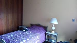 1 dormitorio con cama morada y lámpara en Maya, en Valdivia