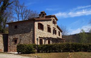 an old stone building with a chimney on top of it at La Casella antico feudo di campagna in Ficulle