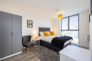 a bedroom with a bed and a chair and a window at GuestReady - A modern getaway in Vauxhall in Liverpool