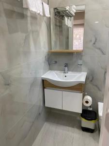 Baño blanco con lavabo y espejo en Persephone, en Himare