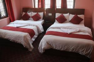 2 camas en una habitación con almohadas rojas. en The hotel mountain Taplejung, en Tāplejung