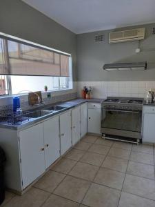 a kitchen with white cabinets and a sink and a stove at The Miller's Airbnb in Cape Town