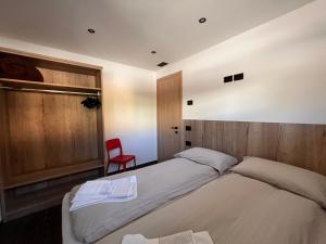 a bedroom with two beds and a red chair at Gin Luxury Apartments City Centre in Livigno