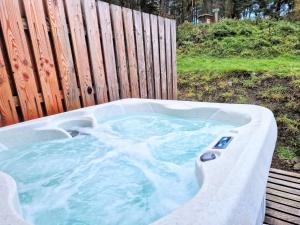 uma banheira de hidromassagem ao lado de uma cerca de madeira em Kaoglen-Blossom-Hot tub-Cairngorms-Pet Friendly em Balnald