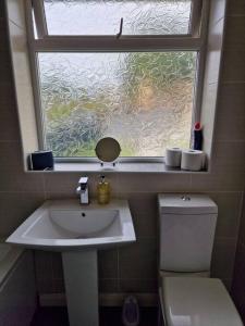 a bathroom with a sink and a window and a toilet at Home in Melton Mowbray in Melton Mowbray