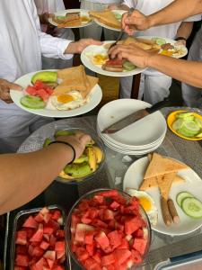 un grupo de personas de pie alrededor de una mesa con platos de comida en BnB Royal Tourist House, en Katmandú