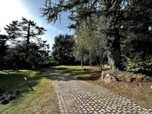 een geplaveid pad in een park met bomen bij La Casa dei Sette Nani in Germignaga