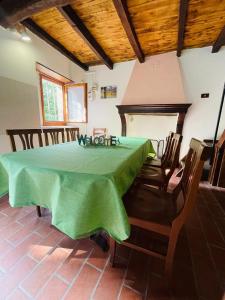 une salle à manger avec une table et des chaises vertes dans l'établissement Casa del Viandante Borgo dei Sassi di Roccamalatina, à Guiglia