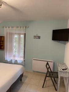 um quarto com uma cama, uma televisão e uma cadeira em Le Haut Pont de la Baie em Mont-Dol