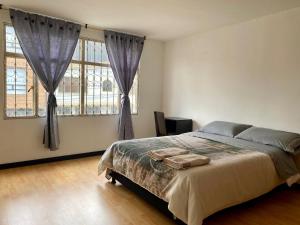 a bedroom with a large bed and two windows at Casa Bianca in Bogotá