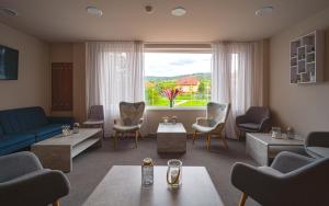 Hotel Aréna في Brumow: غرفة معيشة مع أريكة زرقاء وكراسي ونافذة