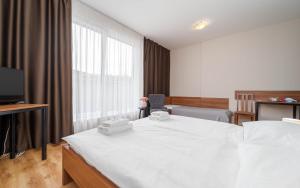 a hotel room with a white bed and a tv at Hotel Aréna in Brumow