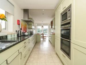 a large kitchen with white cabinets and black counter tops at Pine Lodge - Private Parking in Kingswear