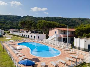 a pool with chairs and umbrellas in front of a building at Residence Emmesse in Zambrone