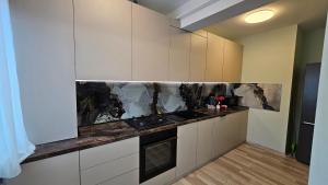 a kitchen with white cabinets and a stove top oven at Nordic Residence 23 in Suceava