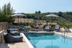 a swimming pool with lounge chairs and umbrellas next to at Sirena Villa in Chania Town