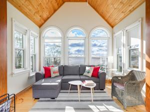 een woonkamer met een grijze bank en ramen bij Stunning waterfront home 25min to downtown Ottawa in Gatineau