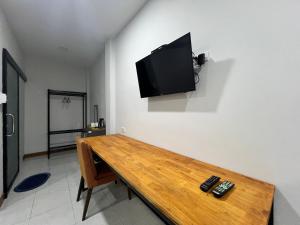 um quarto com uma mesa de madeira e uma televisão na parede em C-Code Resort em Lom Sak