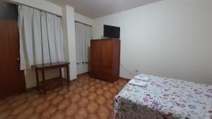 een slaapkamer met een bed en een televisie en een tafel bij HOSPEDAJE D`NOA En el centro de Oxapampa in Oxapampa