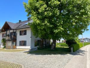 een wit huis met een boom ervoor bij Traumhaft große Ferienwohnung nähe Attersee in Sankt Georgen im Attergau
