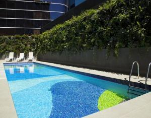 uma piscina com cadeiras ao lado de um edifício em George V Alto de Pinheiros Suite 208 Luxo - Adm Privada - Café da manhã em São Paulo