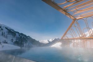 a bridge over a lake with mountains in the background at Hotel Steiner Superior in Obertauern