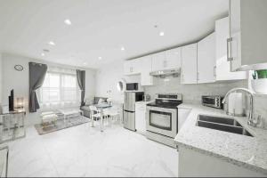 バンクーバーにあるEntire NEW Cozy and Modern 2-storey HOUSEの白いキャビネットとテーブル付きのキッチンが備わります。