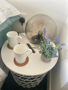 ein weißer Tisch mit zwei Tassen und Blumen drauf in der Unterkunft Private room in Camden in London