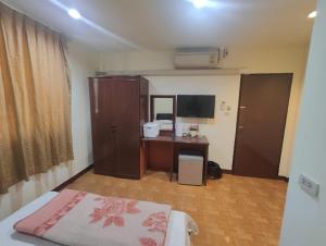 a bedroom with a bed and a desk and a television at OM INN in Bangkok