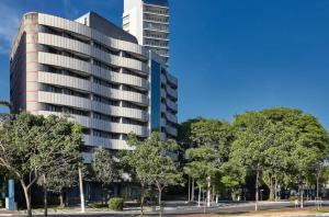 George V Alto de Pinheiros Suite 208 Luxo - Adm Privada - Café da manhã في ساو باولو: مبنى طويل وبه أشجار أمامه