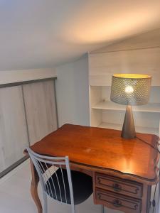 a wooden desk with a lamp and a chair at Belle chambre spacieuse, tropézienne, vue remparts, clim, parking in Aigues-Mortes