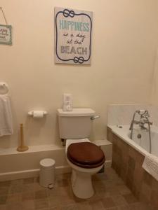 a bathroom with a toilet and a bath tub with a sign at Broadwalk_2 in Coltishall