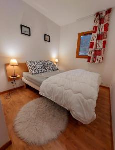 una camera da letto con un letto con un piumone bianco e un tappeto di Le Grand Valmeinier - 6 pers - 2 SDB - 1 terrasse plein sud a Valmeinier