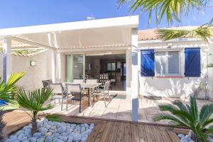 a house with a deck with a table and chairs at VILLA LES PALMIERS in Palavas-les-Flots