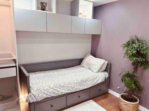 a small bed in a room with two potted plants at Two Bedroom Apartment near Central Line in London