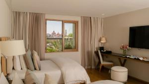a bedroom with a bed and a desk and a window at Cartesiano Boutique & Wellness Hotel in Puebla
