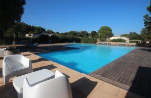 een groot zwembad met witte stoelen en een tafel bij Studio grande piscine dans résidence hôtelière, proche plage in Lecci