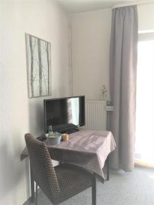 a living room with a table and a tv at Antjes Schmankerlhotel und Restaurant in Tröstau