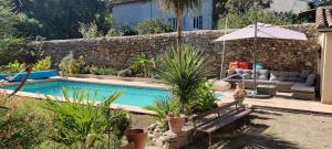 einen Pool mit einem Sofa und einem Sonnenschirm in der Unterkunft St Jean du Gard : Spacious Apartment with Use of Pool in Saint-Jean-du-Gard